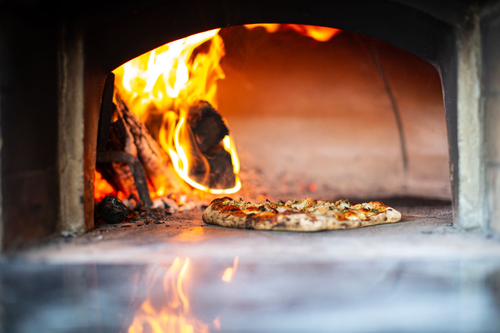 Pizza going into the wood-fired oven